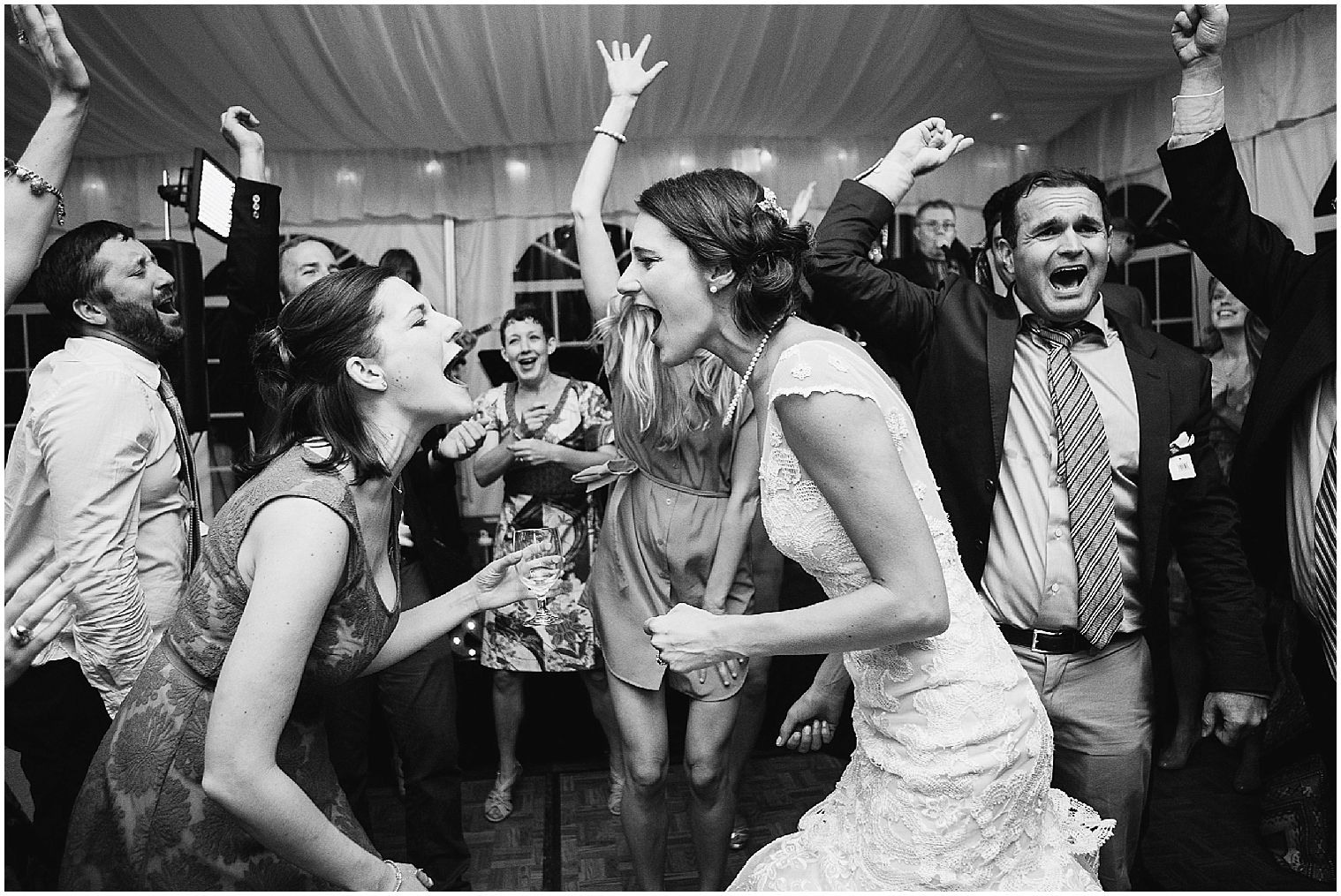 La pareja de novios y los invitados bailan juntos bajo una carpa de recepción en una boda en Keystone Ranch.