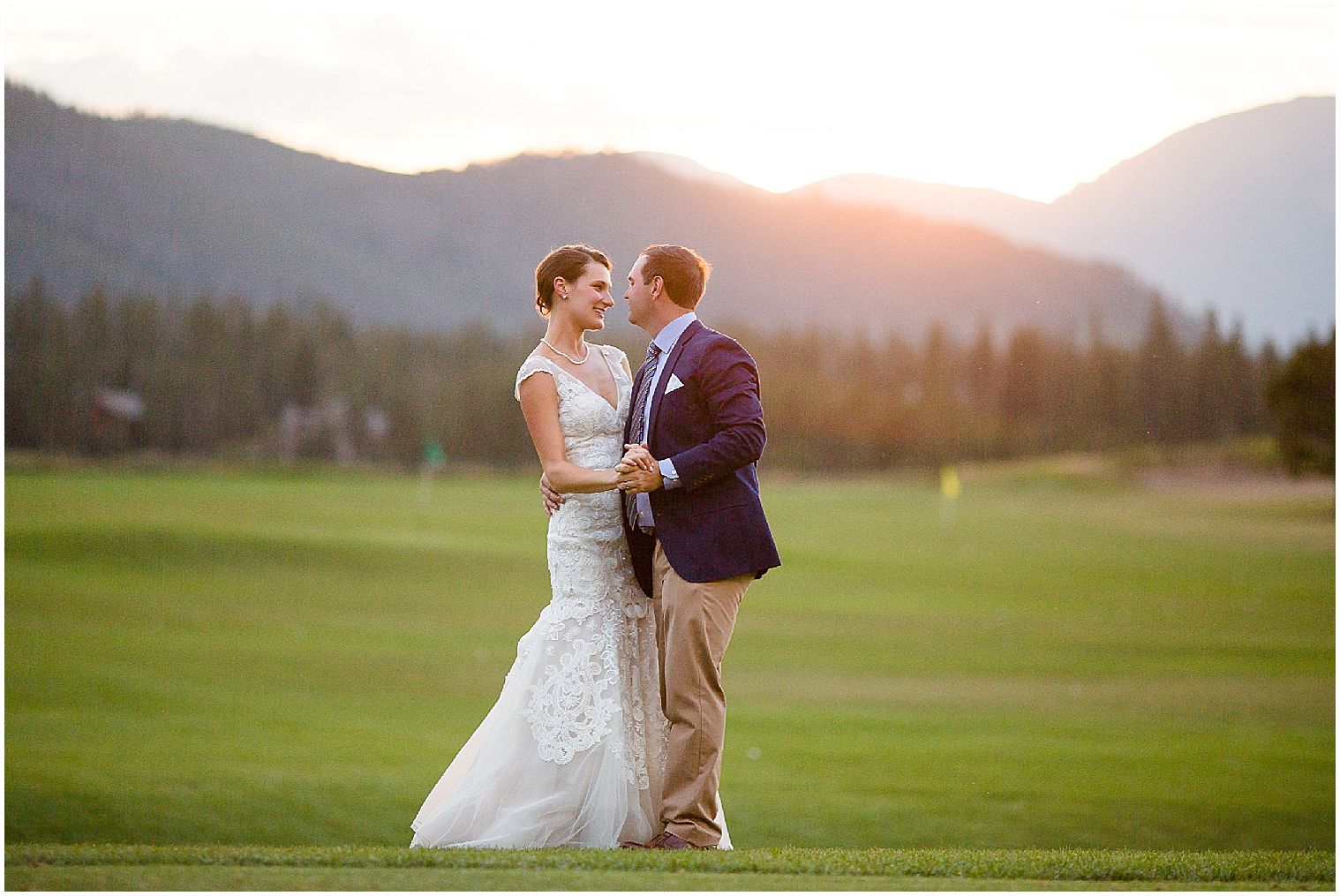  Los novios bailan juntos en el campo de golf al atardecer en su boda en Keystone Mountain.