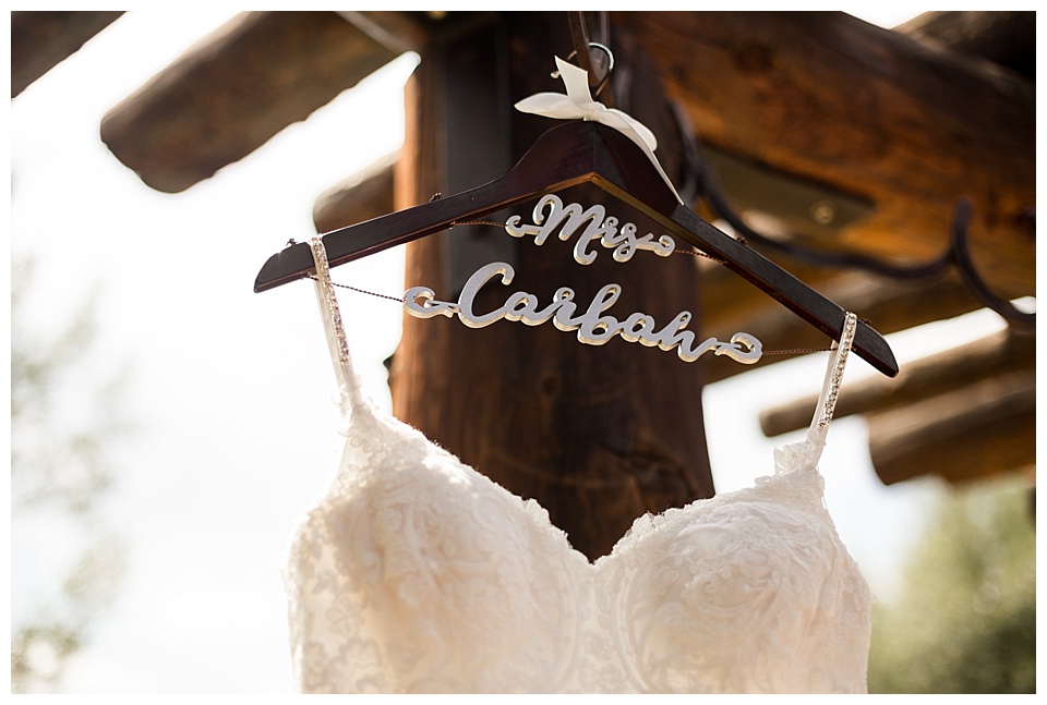 white wedding dress on a personalized hanger hung outside wooden ranch