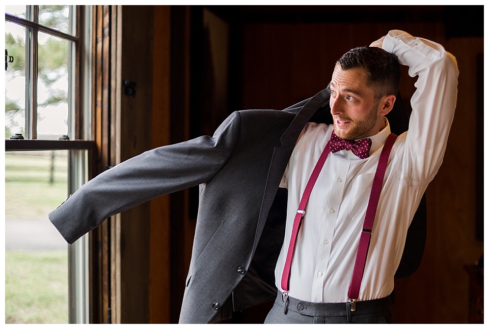 groom putting on his grey suit jacket on his wedding day at spruce mountain ranch