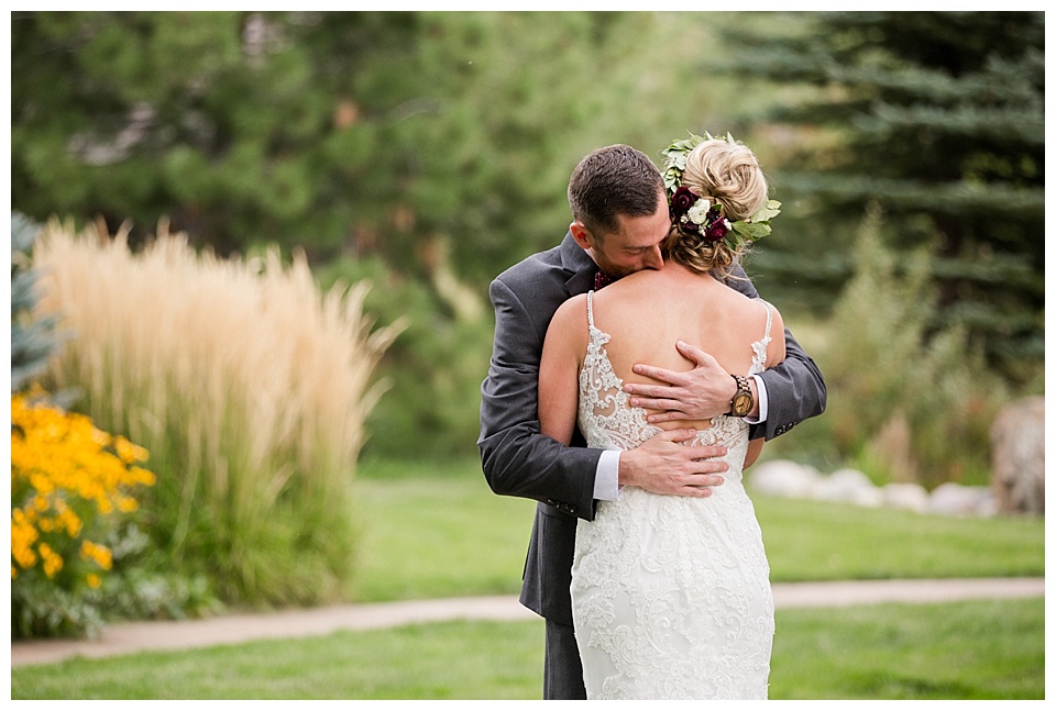 groom hugs bride tightly during their first look at spruce mountain ranch
