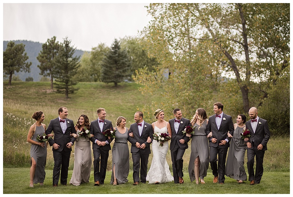 wedding party wearing black and grey walking and laughing at spruce mountain ranch