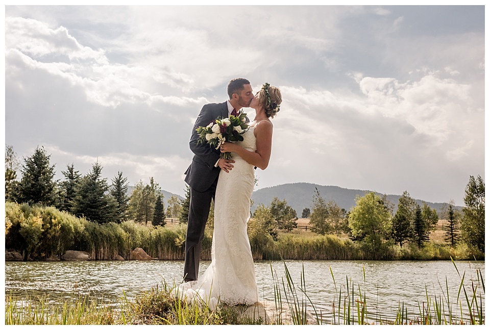 groom dips bride and kiss in front of lake and mountains in colorado