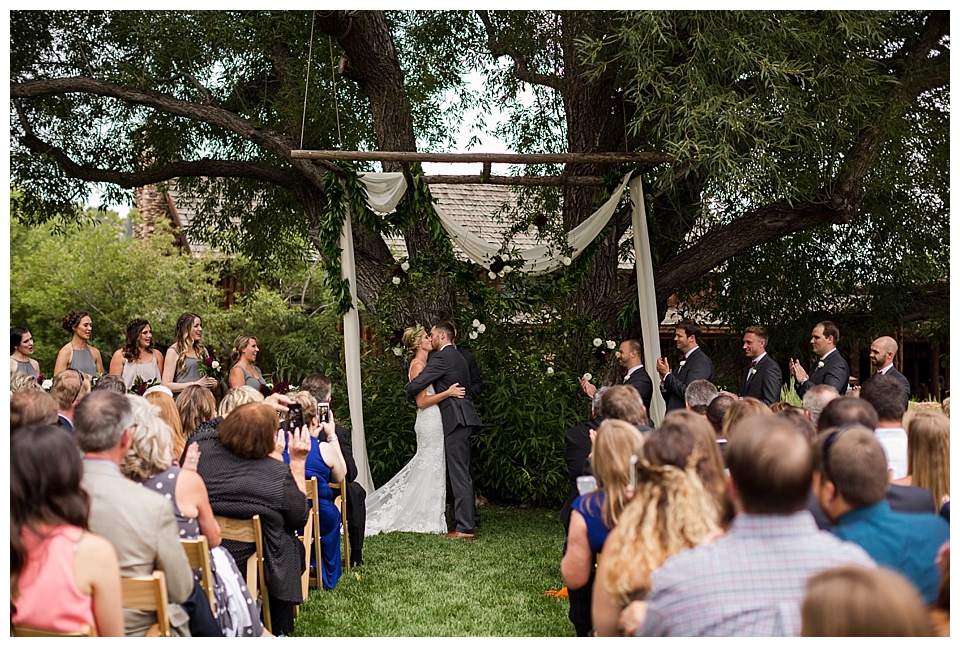 bride and groom share their first kiss as husband and wife at their outdoor wedding ceremony in larkspur colorado