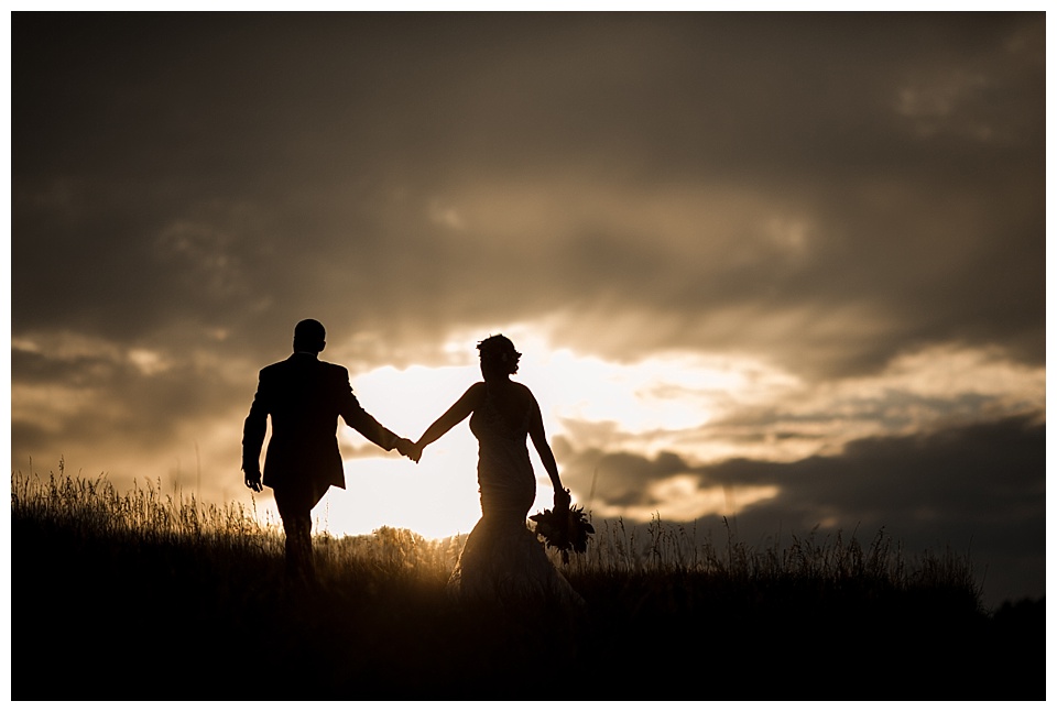 bride and groom silhouette as they walk into the sunset in colorado