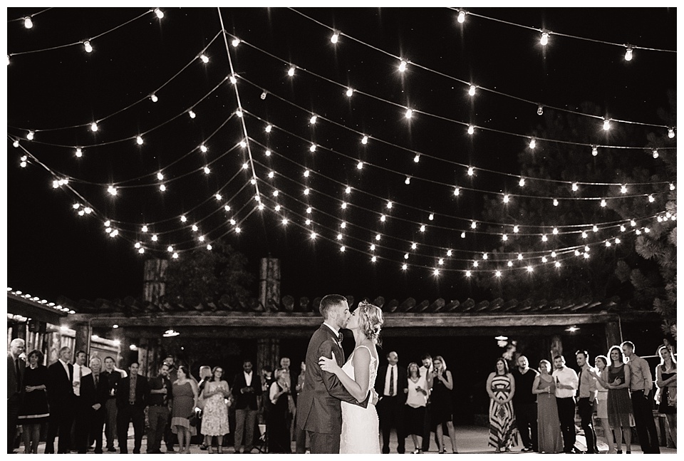 bride and groom kiss during their first dance with twinkle lights