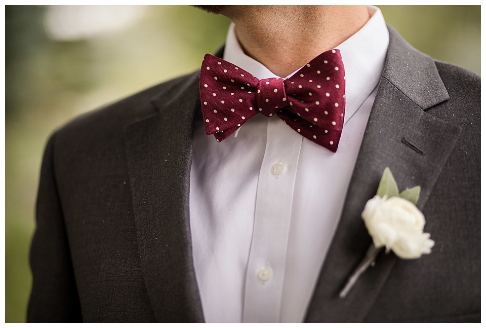detail of groom's red polka dot tie and white flower