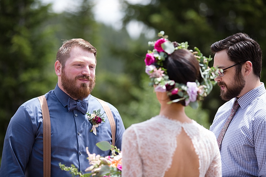 groom looks at bride during ceremony at little nell wedding deck in aspen 
