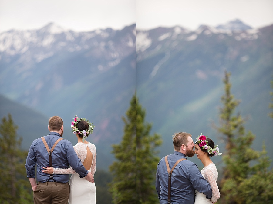 bride and groom hold onto each other at the top of aspen mountain in colorado 