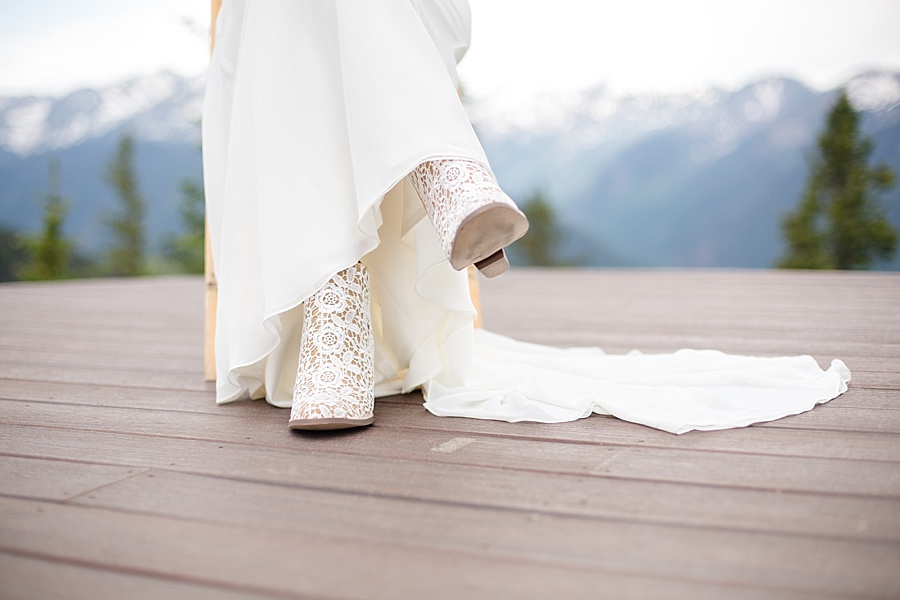 bride shows off her white lace wedding boots at little nell wedding deck in aspen 