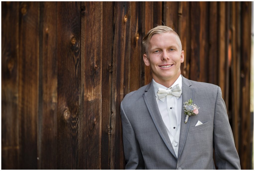 solo shot of groom in front of brown rustic barn at keystone ranch Colorado