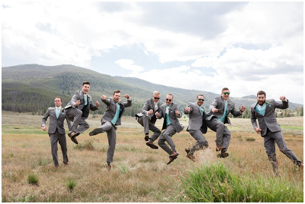 groom and groomsmen jumping during portraits with Colorado mountains in background