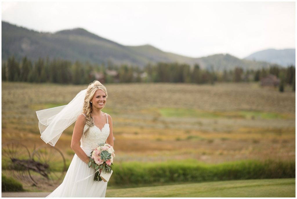 bride smiling in front of Colorado mountains with her bridal bouquet