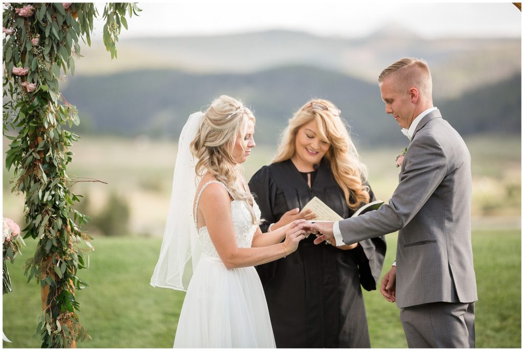 bride and groom exchanging rings during their wedding ceremony in the Rocky Mountains