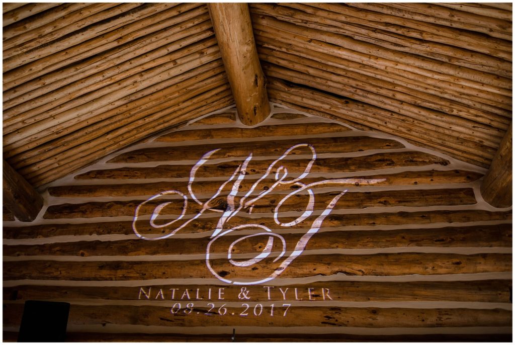 personalized monogram of bride and grooms initials hologram on wooden lodge wall