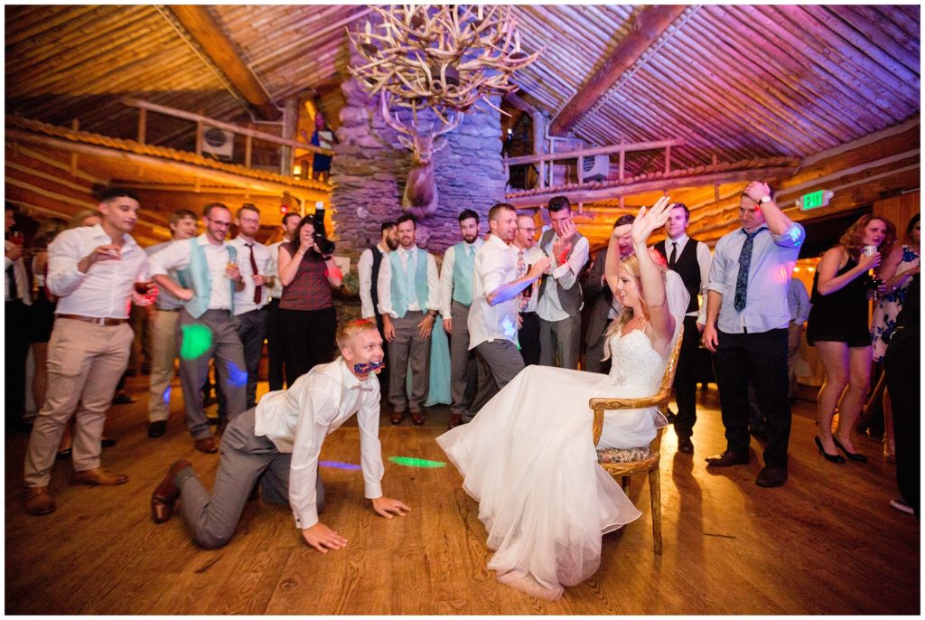 groom crawling on floor while getting garter off bride
