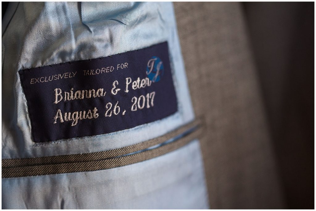 inside of groom's jacket with custom made tag embroidered with names and wedding date