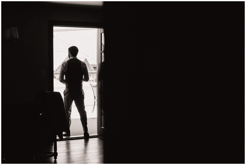 dramatic lighting photo of groom looking out on his wedding day