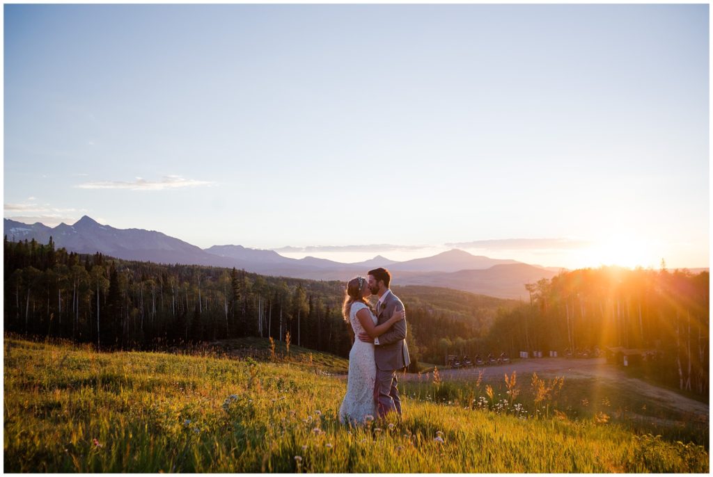Colorado mountain wedding photographer captures bride and groom kissing in the sunset with mountain backdrop