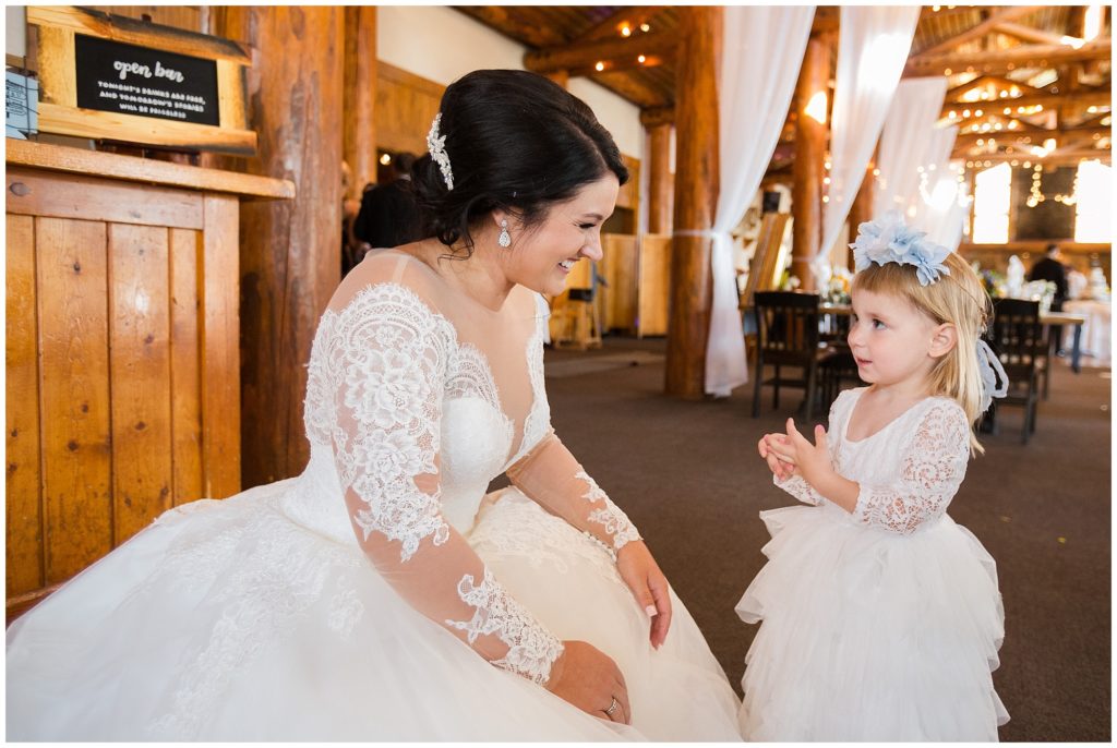 bride sits with adorable flower girl before the wedding ceremony at timber ridge lodge in keystone colorado