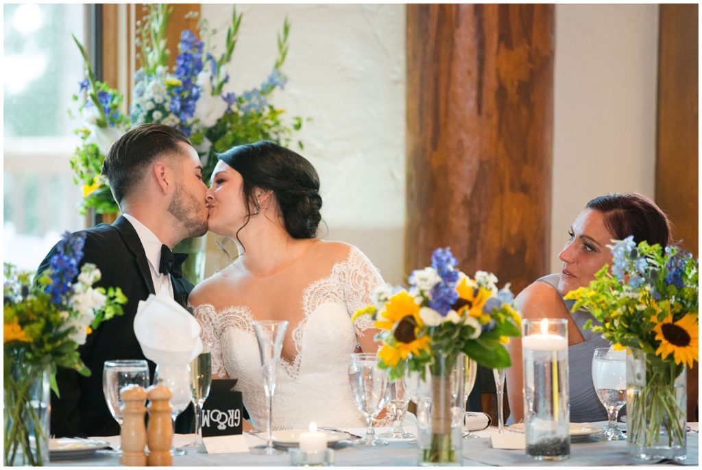 bride and groom kiss during wedding reception toasts at timber ridge lodge 