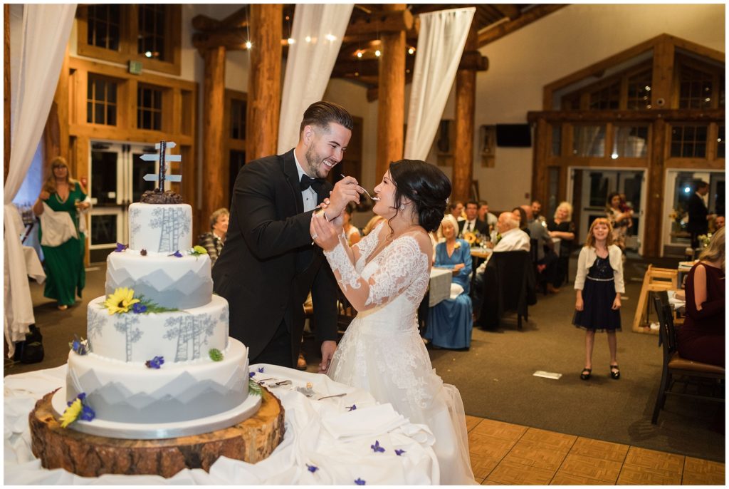 groom feeds bride a piece of their wedding cake at timber ridge lodge