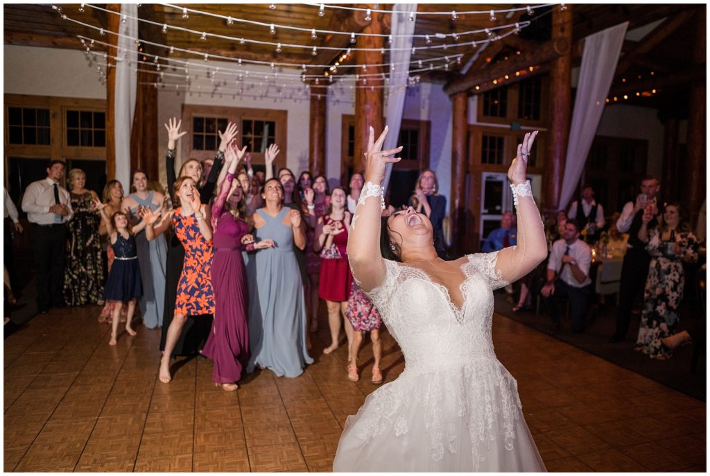 bride cheering as she throws her flowers for the bouquet toss