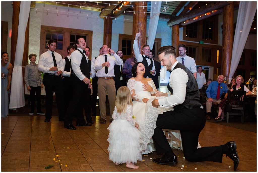 flower girl crashes groom taking garter off bride during their wedding reception 