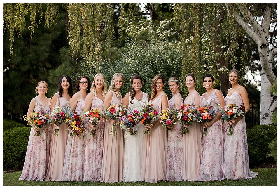 bride poses with her bridesmaids wearing pink floral bridesmaid dresses