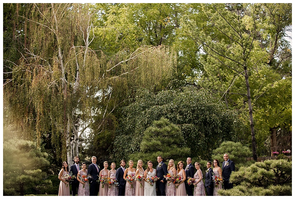 bridal party wearing pink and navy posing in greenery at denver botanic gardens 