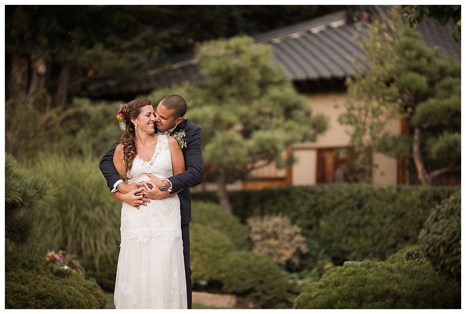 groom touches brides nose from behind her at denver botanic gardens 