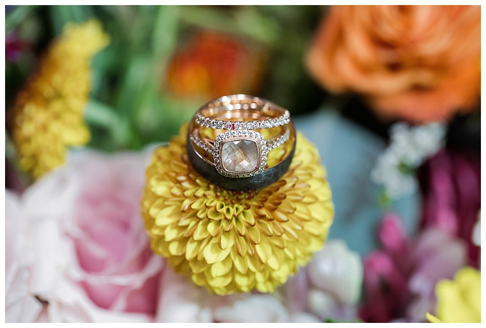 detail of wedding rings on top of colorful flowers 