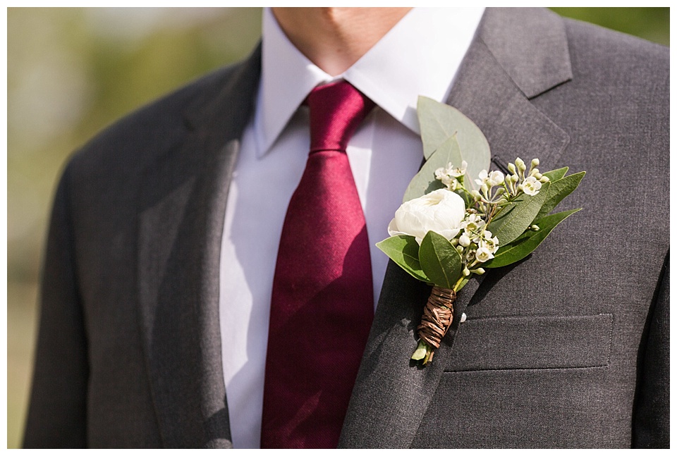detail of groom's boutonniere with red tie and white flowers 