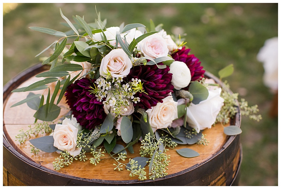 wedding detail of bidal bouquet on top of rustic barrel 