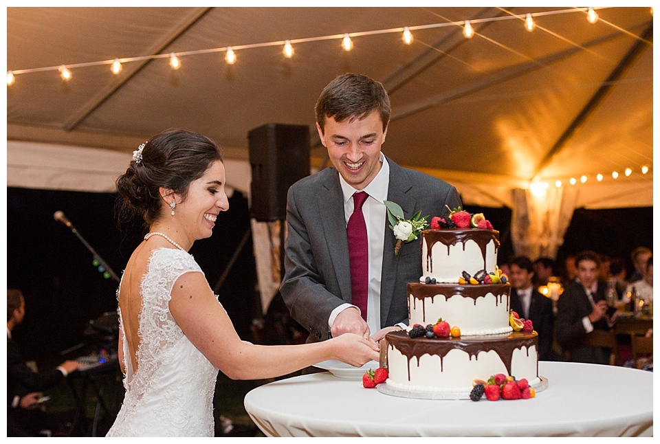 bride and groom cut into their white wedding cake with chocolate and fruit