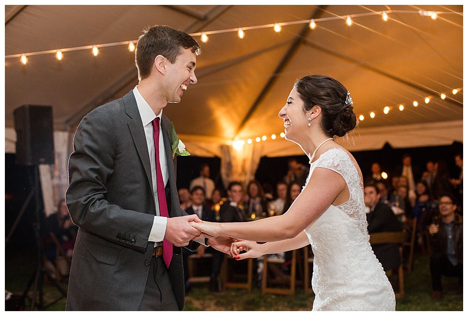 bride and groom share first dance with string lights in a tent