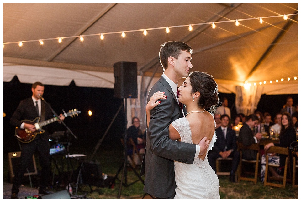 bride and groom dance during their reception in a tent with string lights at oxford road farm