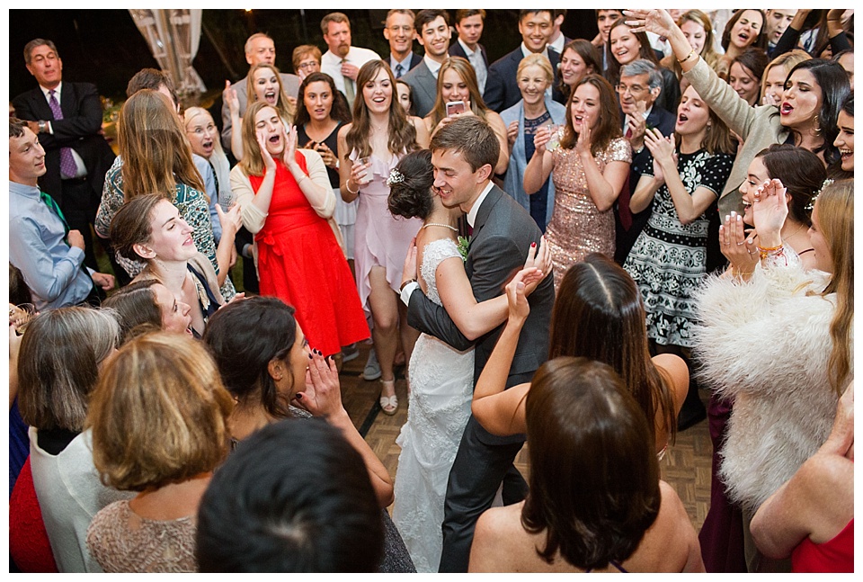 bride and groom surrounded by family and friends on the dance floor of their wedding reception