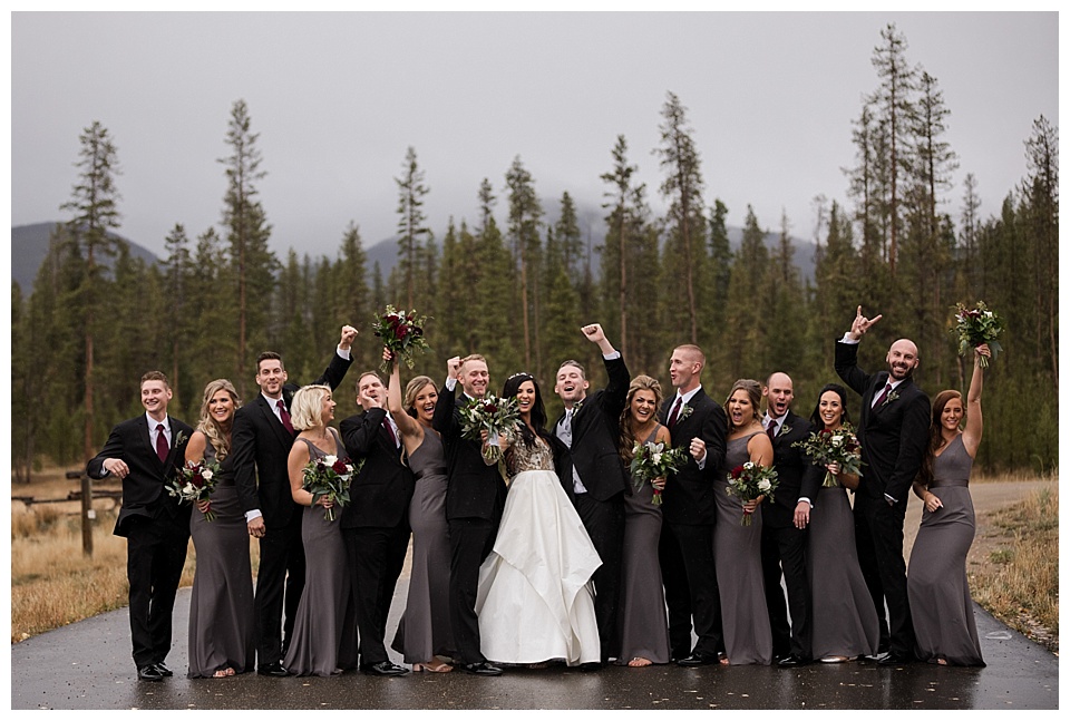 bridal party wearing black and grey cheer after wedding ceremony
