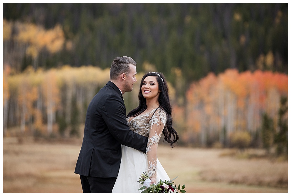 groom holds bride during their portrait session with fall colors at devils thumb ranch