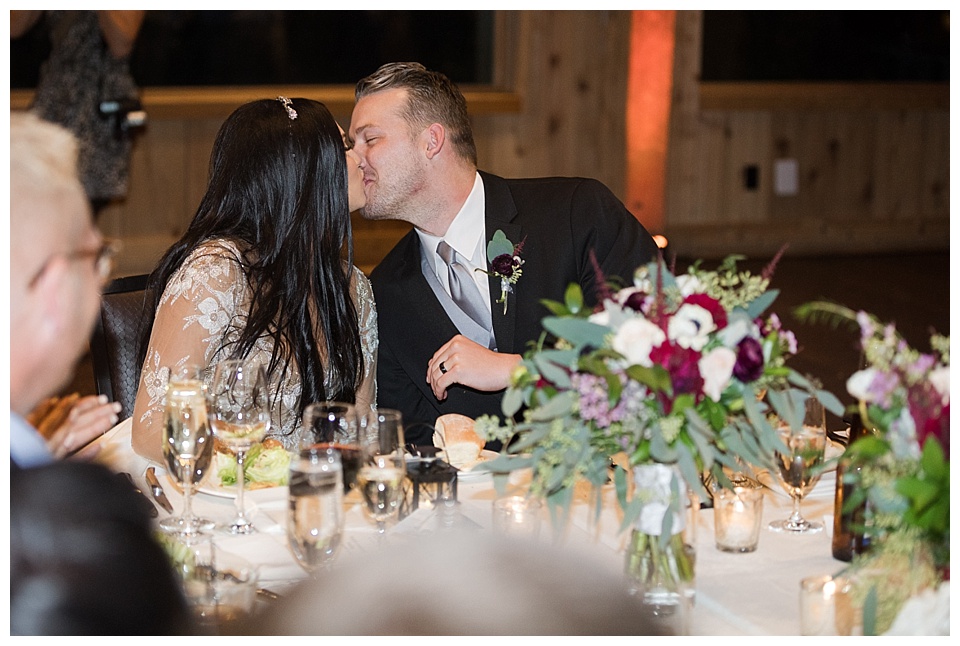 bride and groom kiss during reception toasts