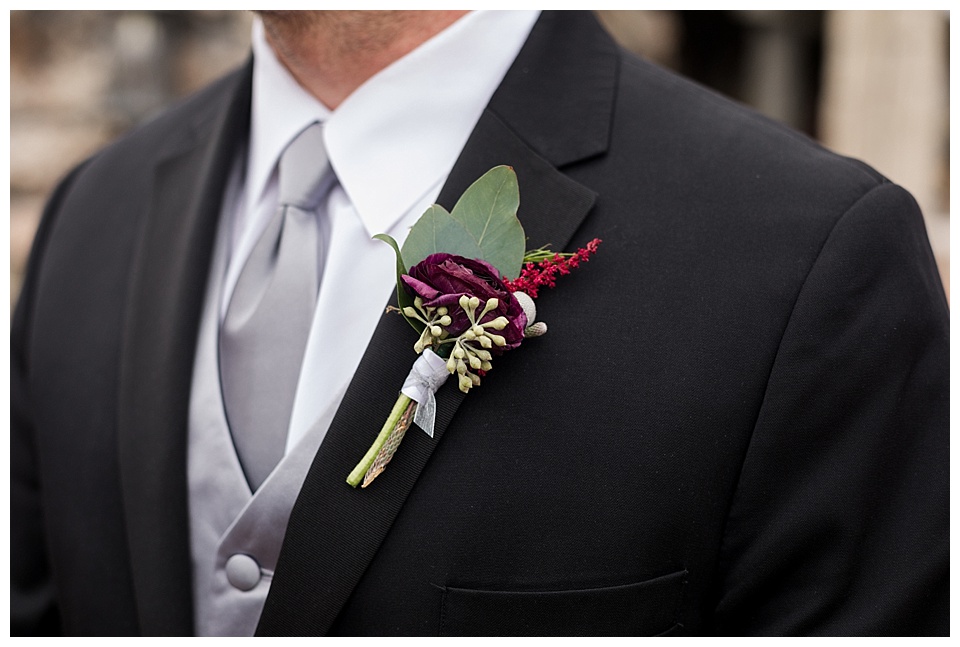 detail of grooms boutonniere with grey tie and red flower 