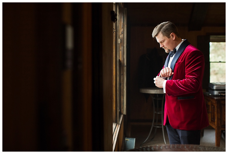 groom putting on his red velvet jacket at spruce mountain ranch