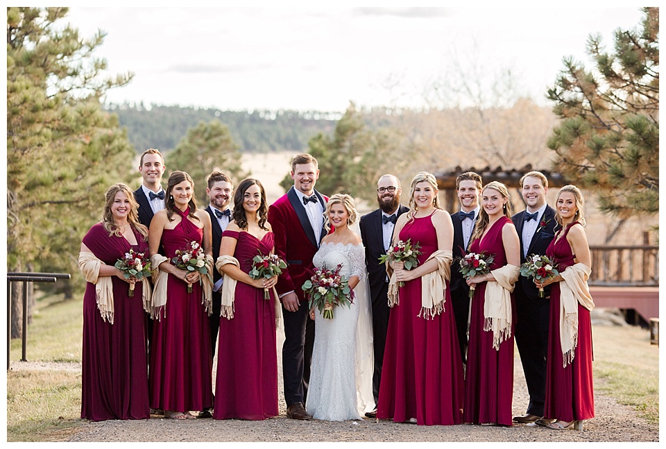 bridal party poses with bride and groom wearing black and red 