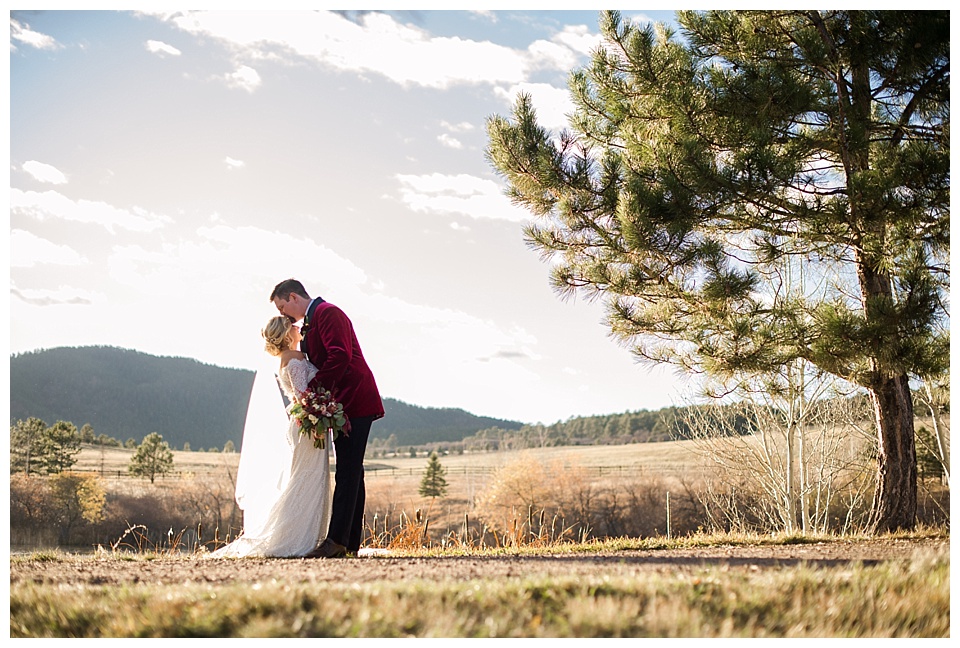 tall groom kisses short bride in the meadow at spruce mountain ranch