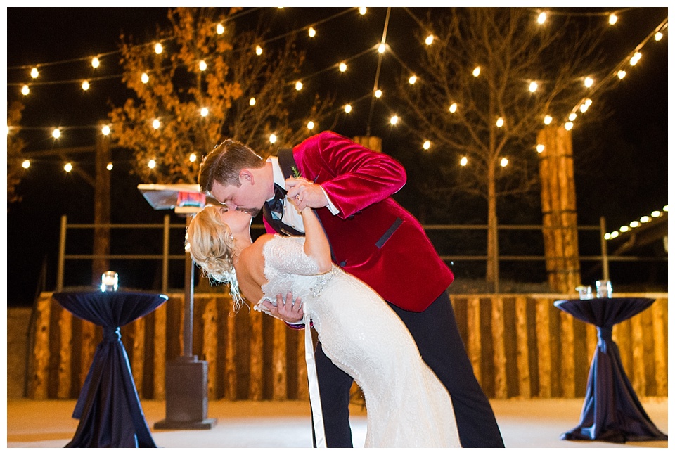 bride and groom kiss while groom dips bride with string lights at spruce mountain ranch