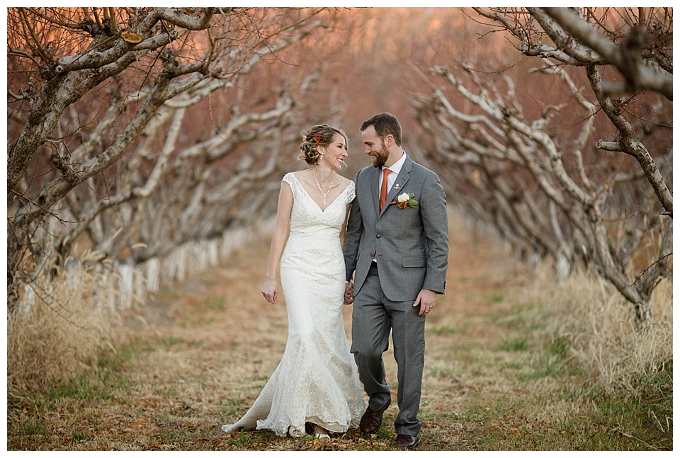 bride and groom smile at each other while walking through colterris winery at sunset