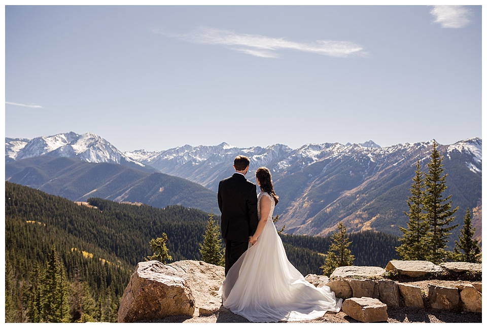 bride and groom look off into the distance on the mountaintop in aspen