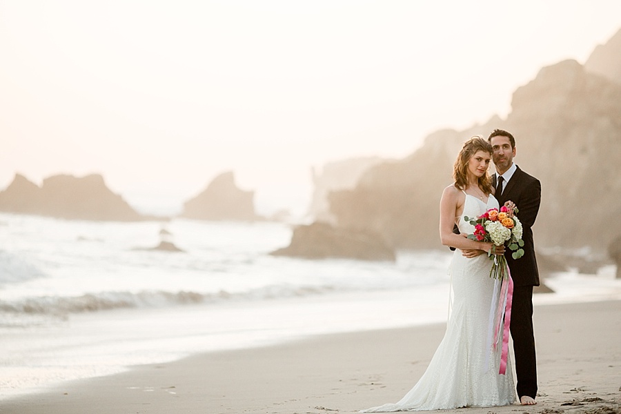 bride and groom pose at matador beach at sunset