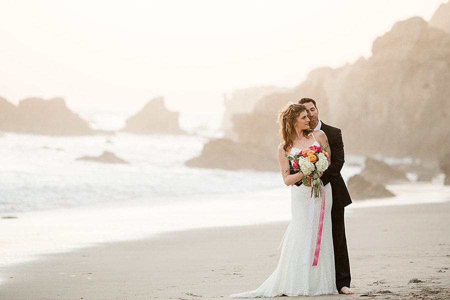 bride and groom hold each other at matador beach california 